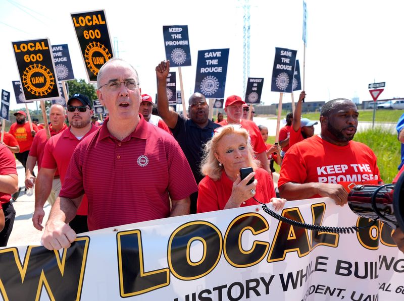 UAW president Shawn Fain, left, and Rep. Debbie Dingell (D-Mich.) yell and march down Dix in Dearborn with Local 600 on Thursday, August 14, 2025 from their headquarters to the Cleveland-Cliffs plant nearby where 600 workers are being laid off due to weak US auto production.