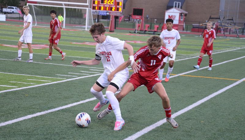 Bedford's Carter Allison (left) and AJ Wells of Monroe battle for the ball during a 5-3 Bedford victory on Tuesday, Aug. 19, 2025.