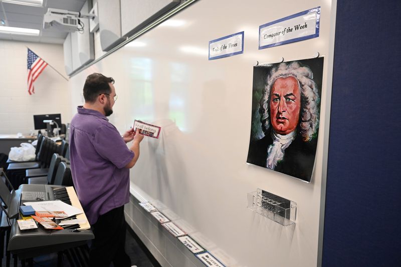 DeKeyser Elementary music teacher Connor Cummins prepares his classroom for the upcoming school year. At right is a copy of a painting of composer Johann Sebastian Bach, who Cummins said will be the “composer of the week” when school begins. Photo taken on Thursday, Aug. 21, 2025, in Sterling Heights, Mich.