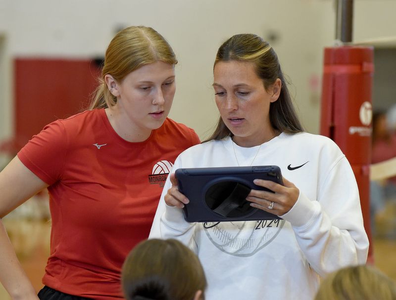 New Monroe head coach Chloe Maurer (left) and Whiteford head coach Janie Valdez take a look at the scoring in a pool play match Friday, August 29, 2025 at Bedford.