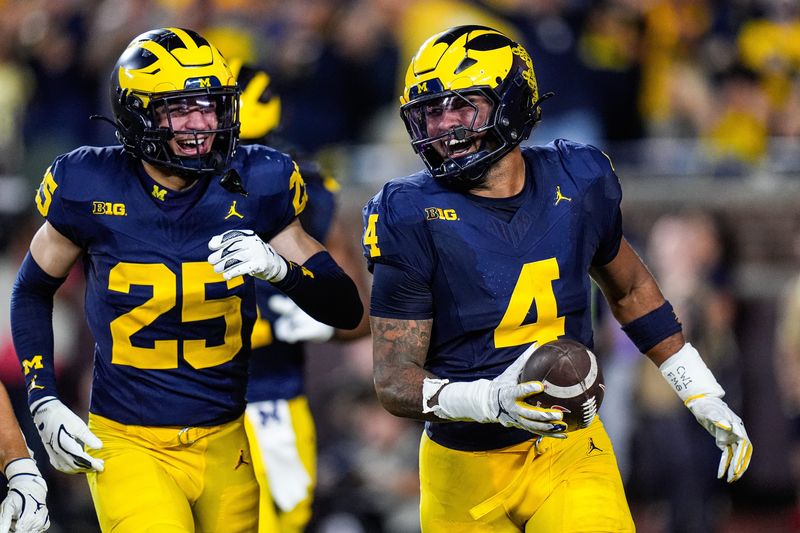 Michigan edge TJ Guy (4), right, celebrates after intercepting a pass from New Mexico quarterback Jack Layne (not in the photo) during the first half at Michigan Stadium in Ann Arbor on Saturday, August 30, 2025.