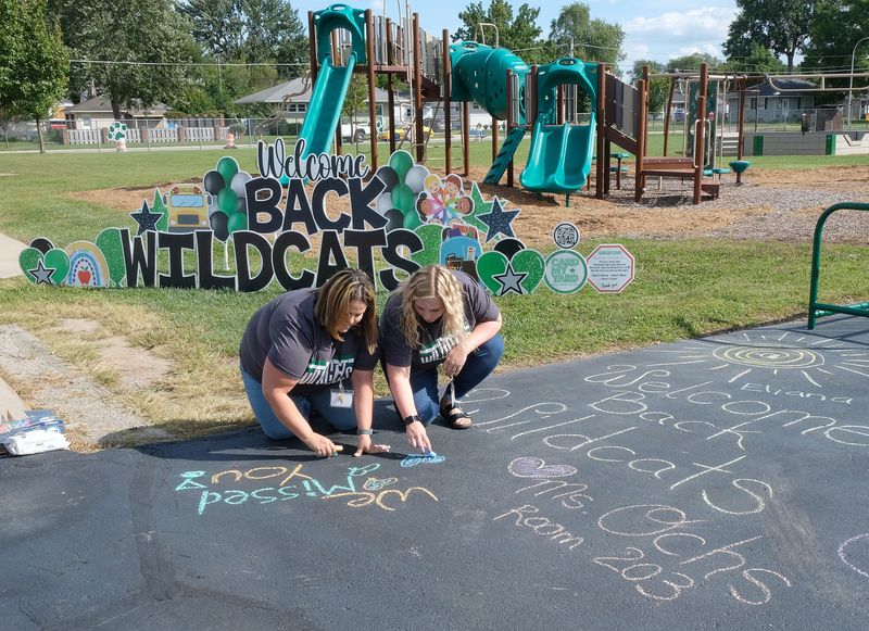 Waterloo Elementary first grade teacher Pauline Schieb and second grade teacher Alysha Vergowven work on a chalk message for the students before the school's open house on Aug. 27. Waterloo was closed last school year for renovations. Schieb was at Custer 1 Elementary last year. Vergowven was at Arborwood South Elementary.