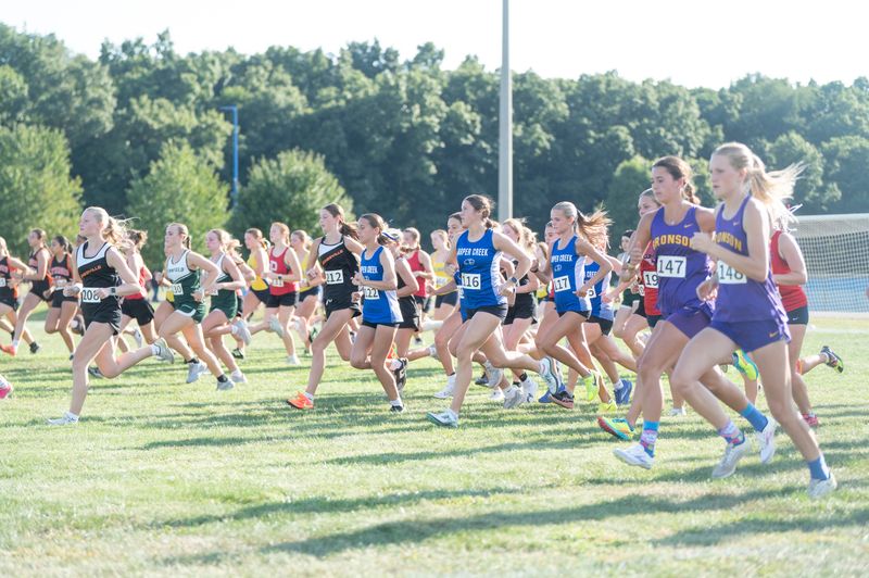 Runners take off from the starting line during the Harper Creek Optimist Club cross country meet at Harper Creek High School on Tuesday, Sept. 2, 2025.