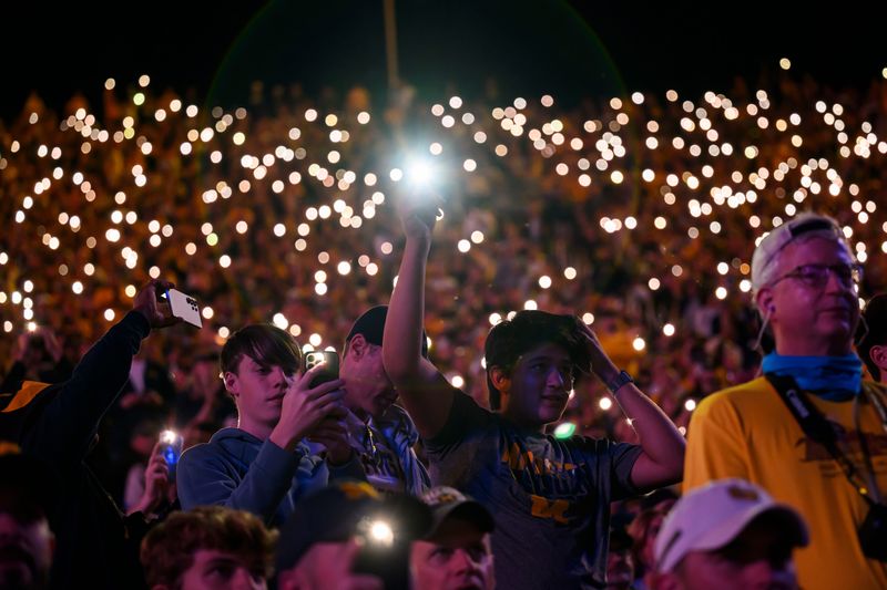 Fans use the flashlights on their cell phones during a Michigan night game last season.