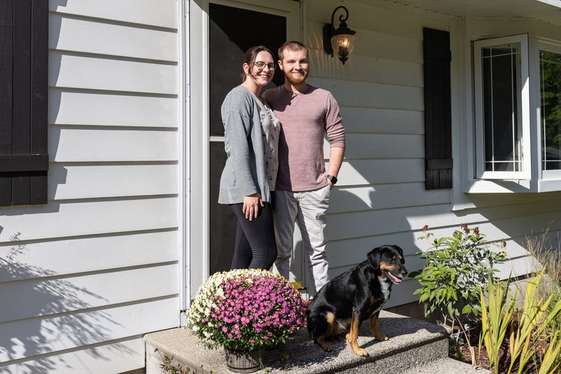 Kellie Hope and Nathan Johnson pose for a photo in front of their new home on Wednesday, Aug. 27, in Grand Haven, Michigan.