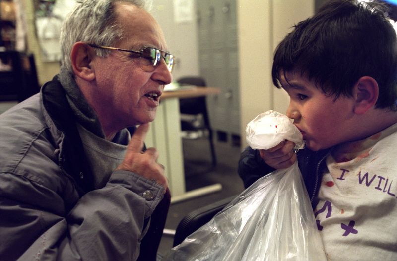 Ignacio "Ziggy" Gonzalez, left comforts Alejandro Lujano, 9, who got whacked accidentally in the lip by a hockey stick, by telling him how he once got it in the chin with a stick in 1947 as a goalie with no mask. "It brings back memories" says Gonzalez who often interacts with the kids that visit the Clark Park ice rink.