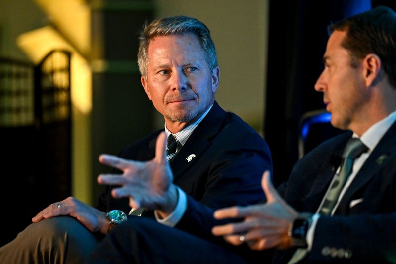 Michigan State University President Kevin Guskiewicz, left, listens as MSU Athletic Director J Batt during a panel discussion hosted by the Lansing Economic Club on Thursday, Sept. 11, 2025, at the Kellogg Center in East Lansing.