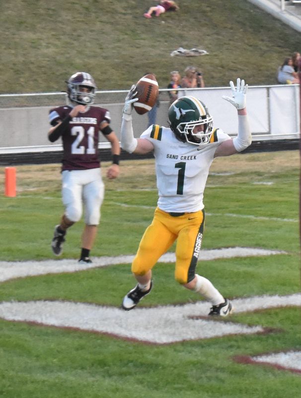 Sand Creek's Wyatt Fox (1) hauls in a touchdown catch while Union City's Kenny Case (21) looks on Friday night