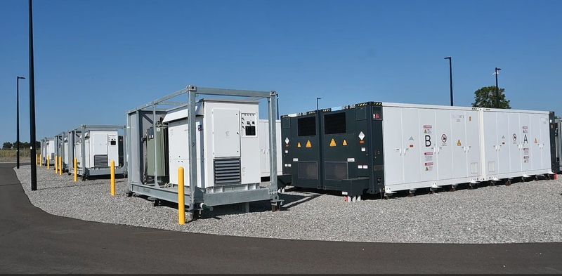 A Power Control Station with attached battery storage containers which convert the electricity back and forth from AC to DC, taking it off the grid for storage.