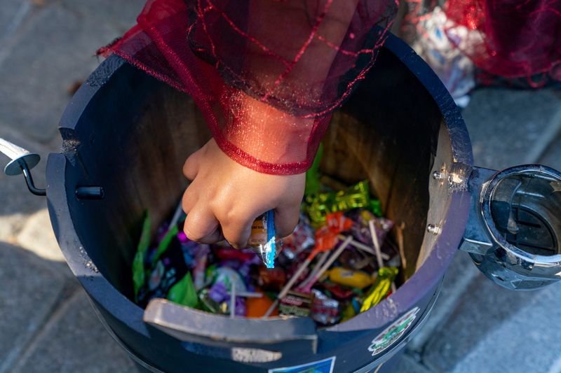 Kids grab candy out of a bucket during the fourth annual Halloween Stroll and Trunk-or-Treat Car Show in downtown Evansville, Indiana on Saturday, Oct. 26, 2024.