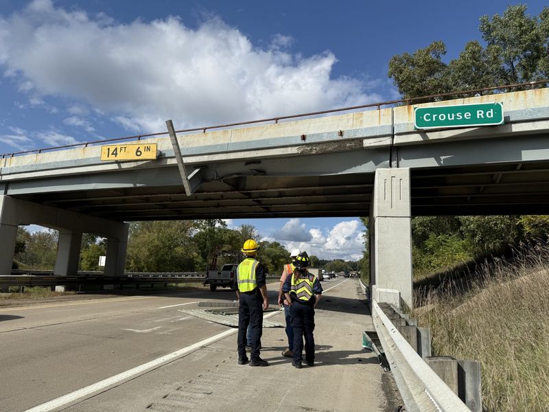An overheight truck hit a bridge and sign on US-23 in Hartland Township, leading to a crash with no injuries.