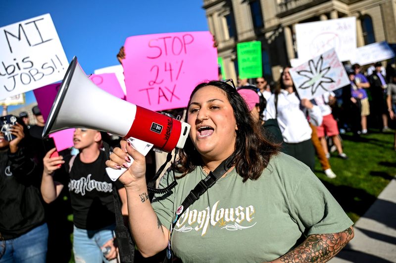 Noura Behnke, of Detroit, with DogHouse Farms Cannabis, leads protesters of House Bill 4951 that would impose a 24% excise tax on the wholesale price of marijuana on Tuesday, Sept. 30, 2025, outside the Michigan Capitol in Lansing.