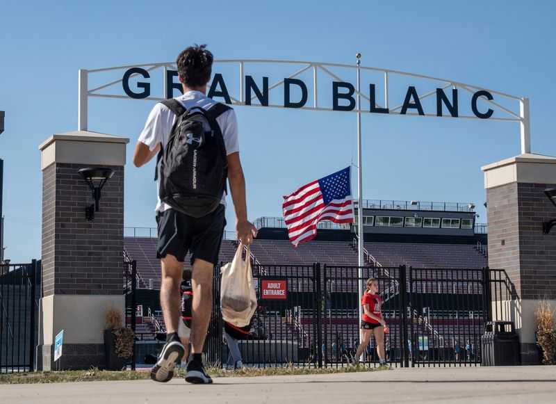 A flag flies at half staff as Grand Blanc High School students head towards the football field before practice on Tuesday, Sept. 30, 2025, as the community works to heal from a mass shooting that took place at nearby The Church of Jesus Christ of Latter-day Saints in Grand Blanc Township on Sunday.