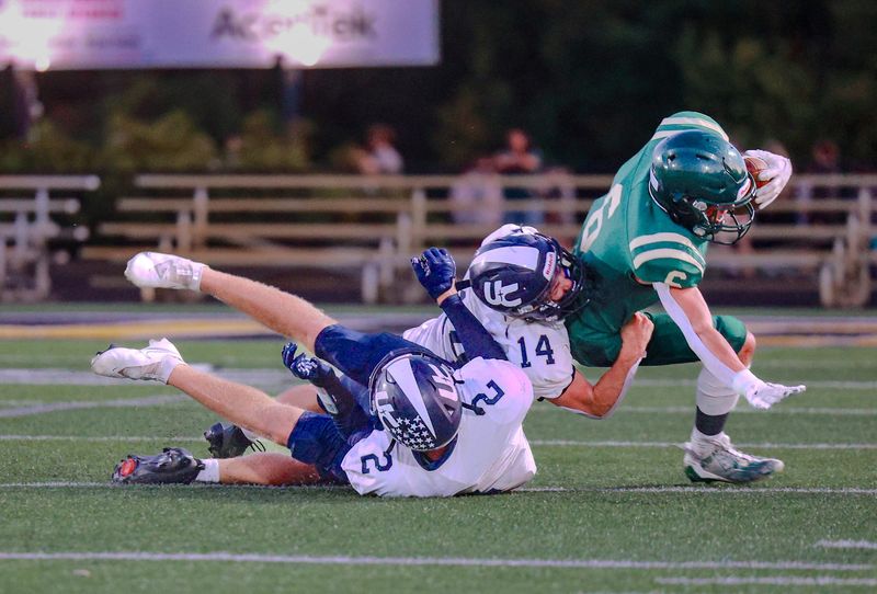 Zeeland West's Brandon Holman, right, tries to escape Unity Christian tacklers. The Dux will play at Niles in the first round of the playoffs.