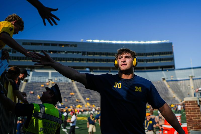 Michigan linebacker Jimmy Rolder (30) high fives fans before a game against Wisconsin at Michigan Stadium in Ann Arbor on Saturday, Oct. 4, 2025.