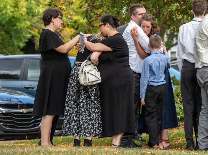 People embrace after the casket of the late Craig Hayden, who was killed during a mass shooting at The Church of Jesus Christ of Latter-day Saints in Grand Blanc Township, is loaded into a hearse at the end of his funeral service held at the The Church of Jesus Christ of Latter-day Saints Flint ward in Flint on Monday, October 6, 2025.
