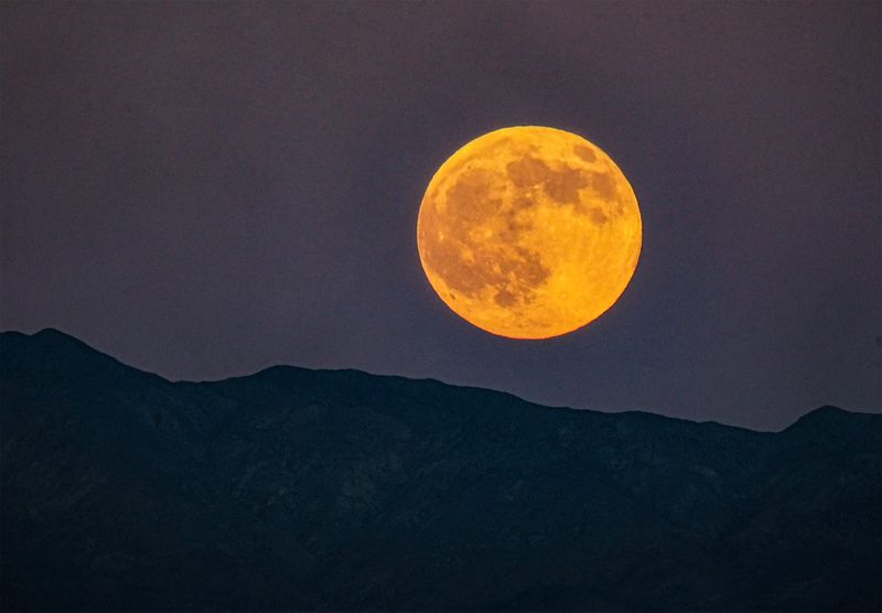 The Harvest moon rises over the Little San Bernadino Mountains as seen from Palm Desert, Calif., just after sunset on Oct. 6, 2025.