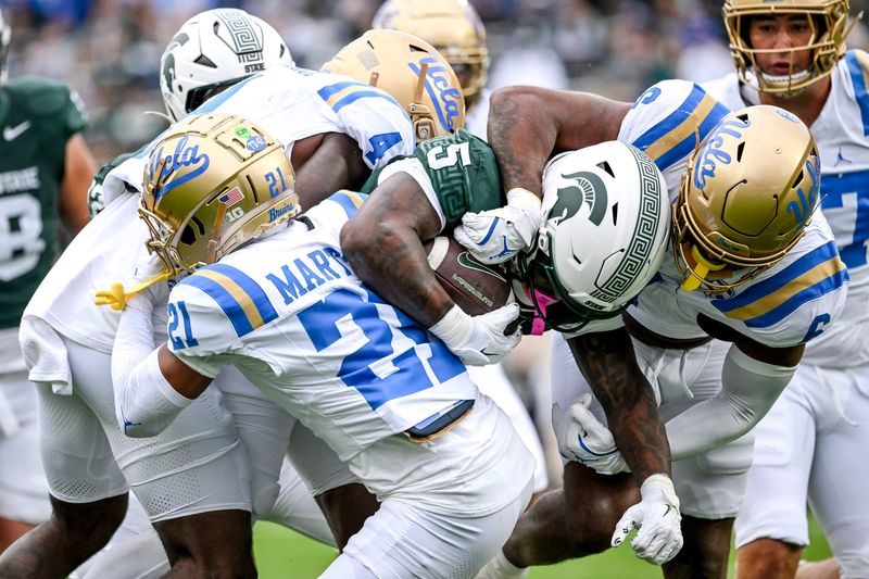 Michigan State's Makhi Frazier, center, is tackled by UCLA after a gain during the first quarter on Saturday, Oct. 11, 2025, at Spartan Stadium in East Lansing.