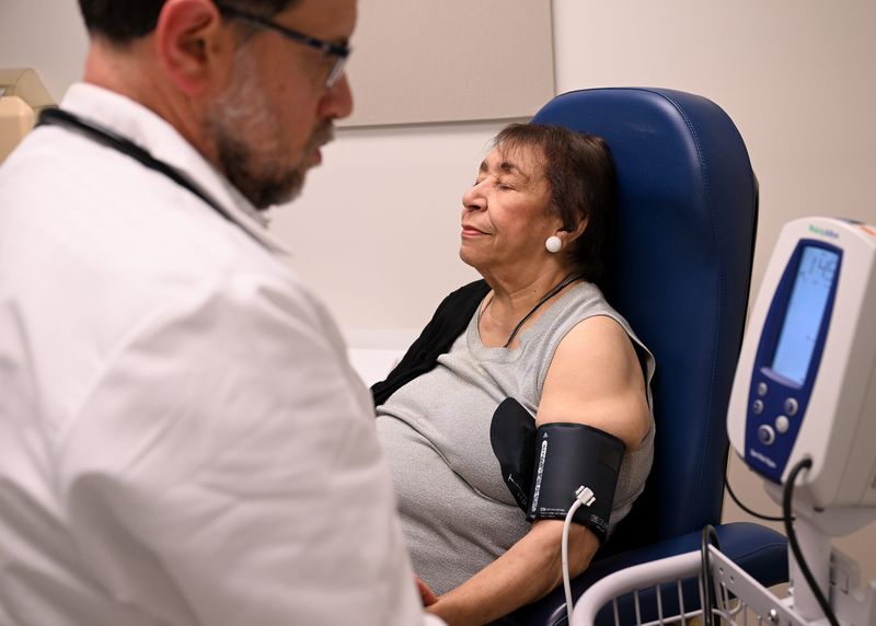 Althea Anderson, 84, of Detroit relaxes and closes her eyes as Dr. Mirza Beg, division head of geriatrics at Henry Ford Health, left, checks her blood pressure at Henry Ford Medical Center- Livonia in Livonia, Mich. on Tuesday, October 14, 2025.