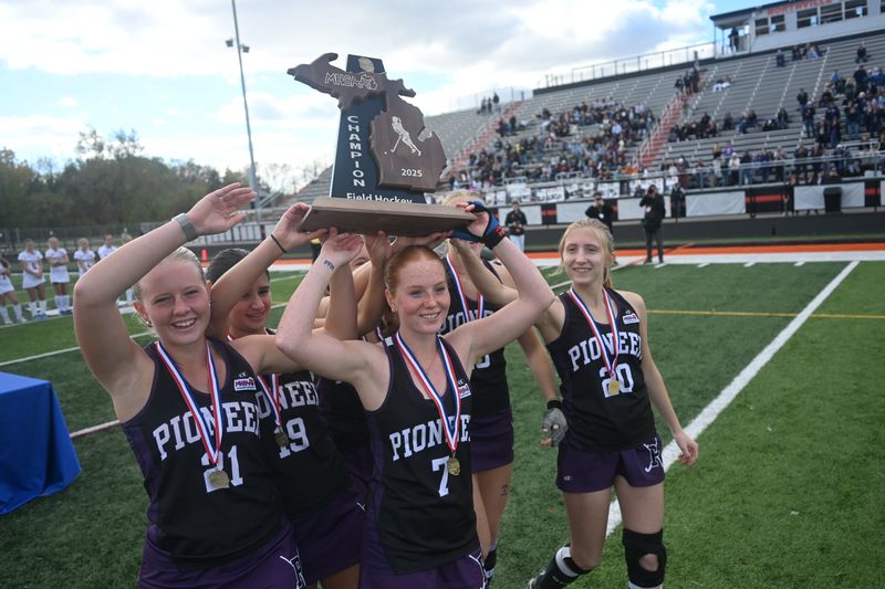 Ann Arbor Pioneer senior forward Maggie Lamb (7) lifts the MHSAA trophy alongside senior defender Mackenzie Schuitman (21), senior midfielder/forward June Galban (19) and senior defender Peyton Peters (20) on Saturday, Oct. 25, 2025, after defeating Dexter, 2-0, at Tom Holzer Field at Northville High School.