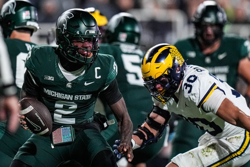 Michigan linebacker Jimmy Rolder (30) tackles Michigan State quarterback Aidan Chiles (2) during the first half at Spartan Stadium in East Lansing on Saturday, October 25, 2025.