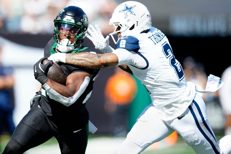 New York Jets running back Breece Hall runs for a first down as Dallas Cowboys safety Juanyeh Thomas attempts to tackle him in the first quarter, Sunday, October 5, 2025.