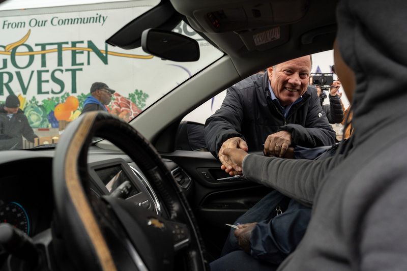Detroit Mayor Mike Duggan greets community members waiting for their cars to be loaded with food items during a community food distribution event at Jesus Tabernacle of Deliverance Ministries in Detroit on Wednesday, Nov. 5, 2025.