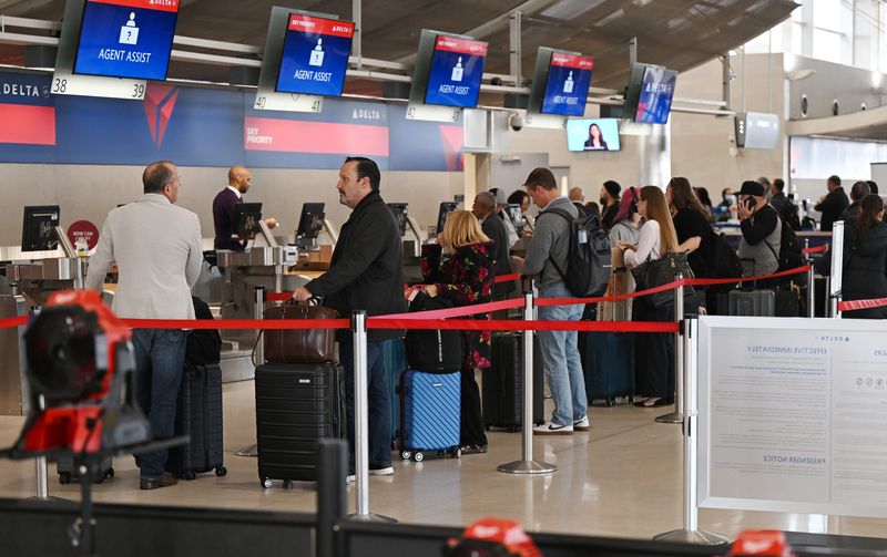 Passengers wait in line to check their luggage before going through the TSA checkpoint to board their flights at McNarmara Terminal on November 6, 2025, in Romulus, MI.