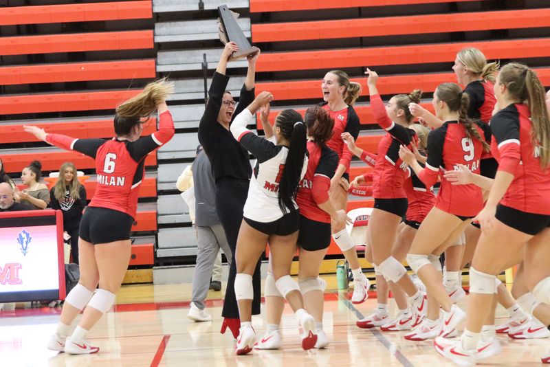 Milan volleyball coach Sarah Eliason hands off the trophy to her players after beating Airport 23-25, 25-21, 25-19, 25-12 in the finals of the Division 2 District at Milan on Thursday, Nov. 6, 2025.