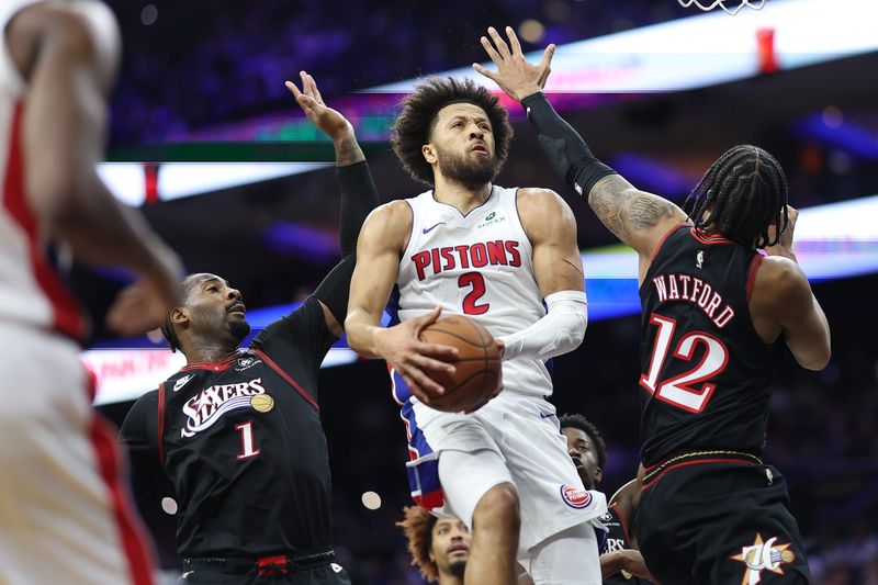 Detroit Pistons guard Cade Cunningham drives for a shot between Philadelphia 76ers forward Trendon Watford (12) and center Andre Drummond (1) during the first quarter at Xfinity Mobile Arena, Sunday, Nov, 9, 2025 in Philadelphia.