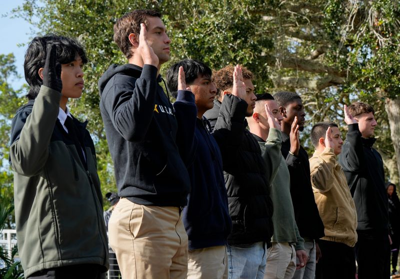 Military recruits raise their hands in an oath of enlistment during a Veterans Day ceremony, Nov. 11, 2025, at Veterans Memorial Island Sanctuary in Vero Beach.