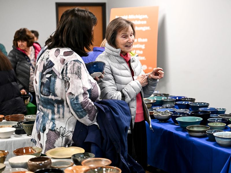 Mary Clausen, right, and Pam O'Farrell browse the selection of handcrafted bowls donated by Greater Lansing Potters' Guild and Clayworks artists during the Empty Bowls benefit at the Greater Lansing Food Bank on Wednesday, Nov. 12, 2025, in Bath Township.