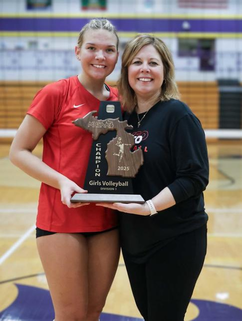 Eleanor Williams (left) stands next to her mother and coach Stacey Williams (right) with district title trophy after defeating Utica Eisenhower, 3-2, on Thursday, Nov. 6, at Avondale High School in Auburn Hills.