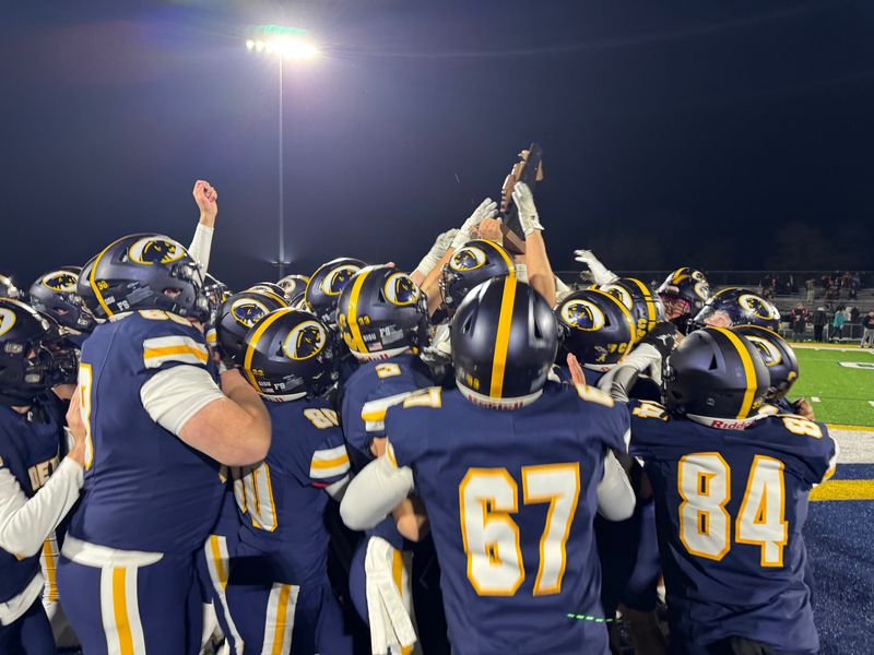 DeWitt players celebrate with their trophy after claiming a Division 3 regional title with a 70-26 victory over Fenton on Friday, Nov. 14, 2025 at DeWitt.