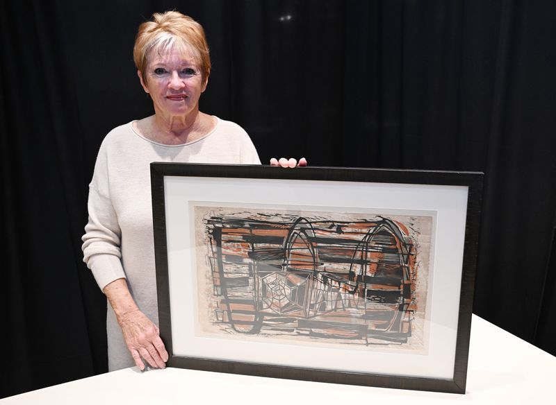 Photo of Susan Williams, 77, of Keego Harbor, with her 1957 Lobster Trap print, during the Trash or Treasure event at the Michigan Design Center on November 14, 2025, in Troy, MI.