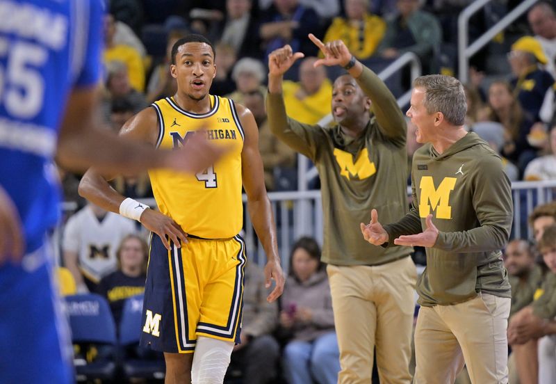 Michigan guard Nimari Burnett (4) talks with head coach Dusty May, right, while assistant coach Mike Boynton Jr. gives instructions in the first half as Michigan takes on Middle Tennesee at Crisler Center in Ann Arbor, Mich. on November 19, 2025.