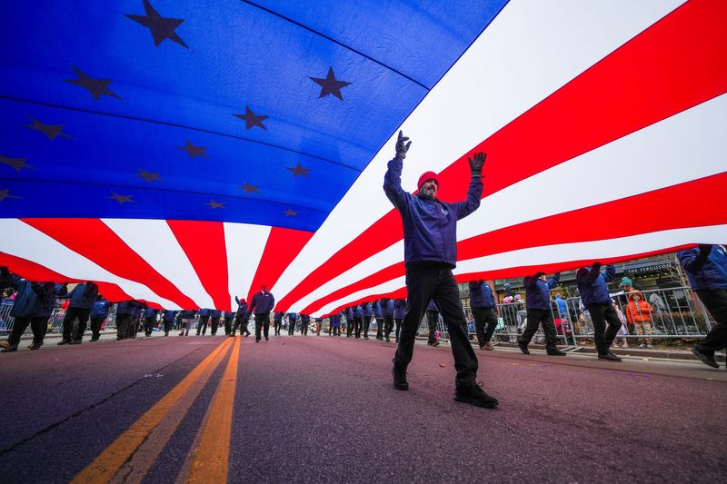 An American flag is carried on Woodward Avenue during the 99th America’s Thanksgiving Parade presented by Gardner White in Detroit on Thursday, Nov. 27, 2025.