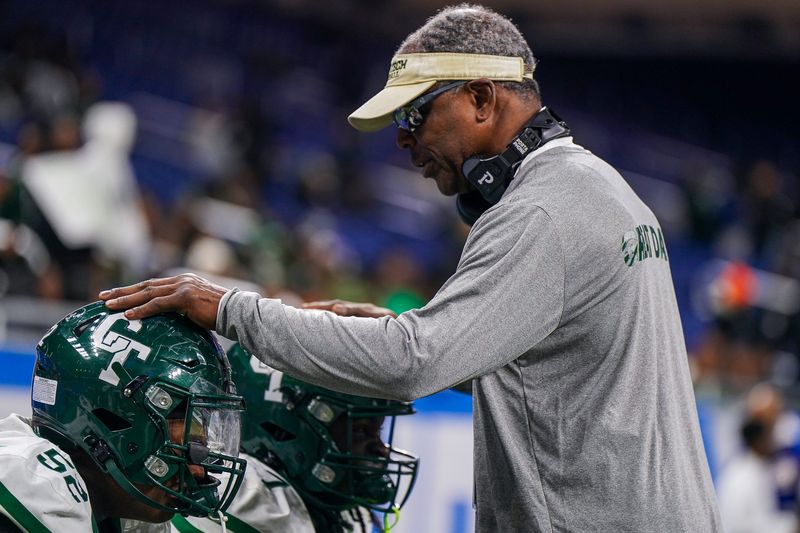 Detroit Cass Tech assistant coach Dwight Blakey Sr. talks with defensive end Antijuan Wilkes Jr. (52) and running back Julian Taylor (7) while facing Detroit Catholic Central in the Division 1 State Championship at Ford Field on Sunday, Nov. 30, 2025. Catholic Central won 42-19.