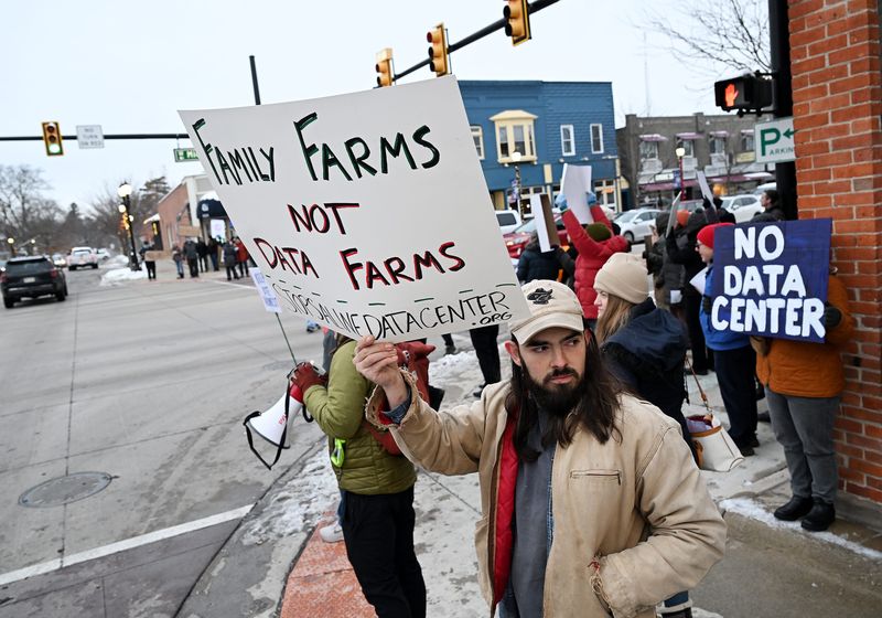 Steven Kurz, 30, of Ypsilanti holds up a sign saying “Family Farms not Data Farms” during a “No Secret Deals for DTE” protest at the corner of Michigan Avenue and Ann Arbor Road in Saline, Mich. on Dec. 1, 2025. The protest is about the data center proposed for Saline.