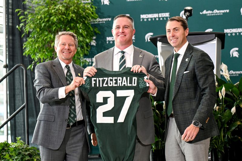 Michigan State football's new coach Pat Fitzgerald, center, holds up a jersey with MSU President KevinÂ Guskiewicz, left, and athletic director J Batt, right, during Fitzgerald's introductory press conference on Tuesday, Dec. 2, 2025, at the Tom Izzo Football Building in East Lansing.
