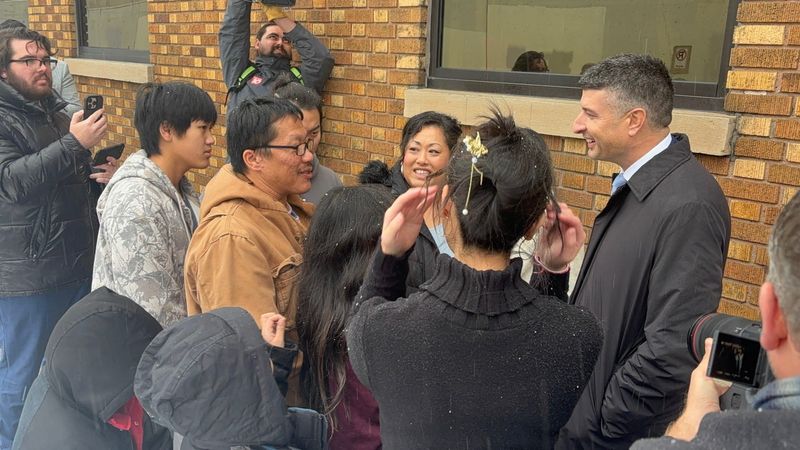 Lue Yang, in a tan coat, greets U.S. Rep. Tom Barrett, R-Charlotte, upon his release in Grand Rapids on Dec. 3, 2025.