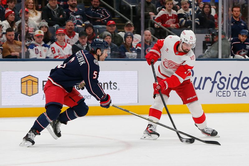 Detroit Red Wings center Dylan Larkin (71) wrists a shot on goal as Columbus Blue Jackets defenseman Denton Mateychuk (5) defends during the first period at Nationwide Arena in Columbus, Ohio, on Thursday, Dec. 4, 2025.