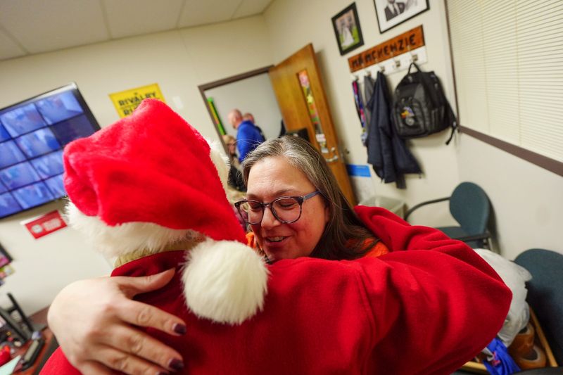 Danielle Prior, 43, of Allen Park, gives secret Santa elf a hug after receiving a gift of $200 from Secret Santa’s elves, that travelled to Lincoln Park from another state, to support the after school store they stock with rewards for students when they earn pride cards after displaying school values, alongside , Monday, Dec. 8, 2025. Minard works as the school social worker and Prior is the media specialist.