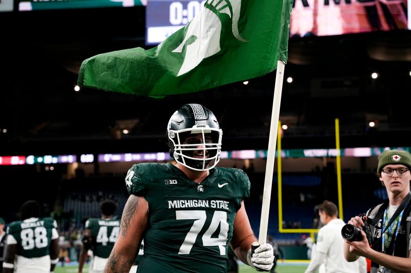 Nov 29, 2025; Detroit, Michigan, USA; Michigan State offensive lineman Gavin Broscious (74) carries a Michigan State flag after defeating Maryland at Ford Field. Mandatory Credit: Brendan Mullin-Imagn Images