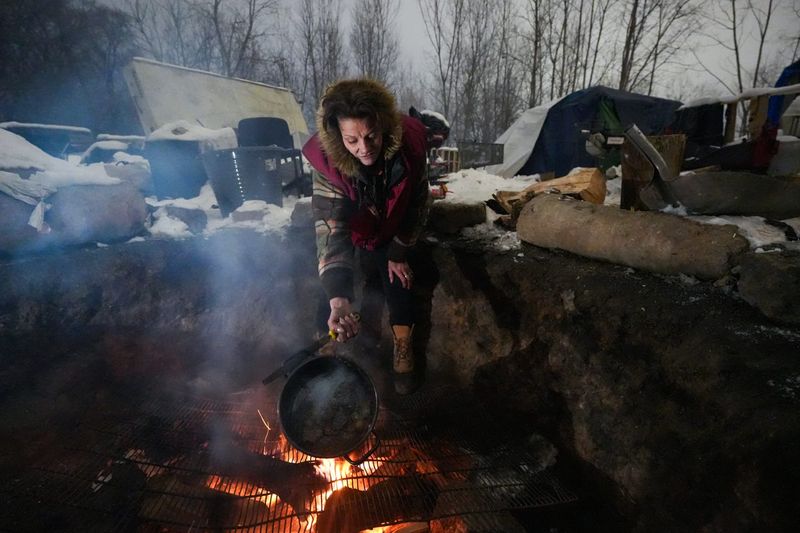 "I am so blessed," two-time cancer survivor Kelly Cole, 39, of Lansing said on Friday, Dec. 12, 2025, while cooking venison stew for herself and neighbor. Raymond Westphal. The stew is made with melted snow, venison roast, carrots, and potatoes. "I've had to learn to walk again, I've had a bone marrow transplant, and survived open heart surgery. Don't ever panic, because God will always come through," Cole says. She has lived at the camp for about six months, she said.