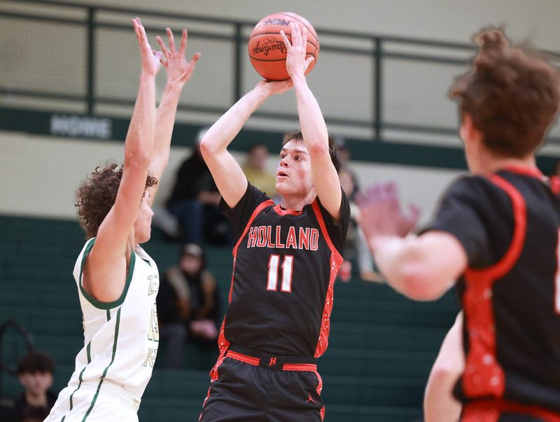 Holland's Keegan Hulst, center, puts up a shot against Zeeland West on Tuesday, Dec. 16, 2025, at Zeeland West.