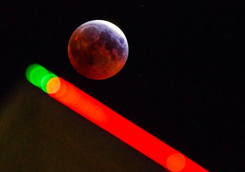 The moon approaching the total eclipse phase with the neon lights that framr the Cocoa Beach Hampton Inn in the foreground. The eclipse of the blood worm moon lunar eclipse Friday morning.
