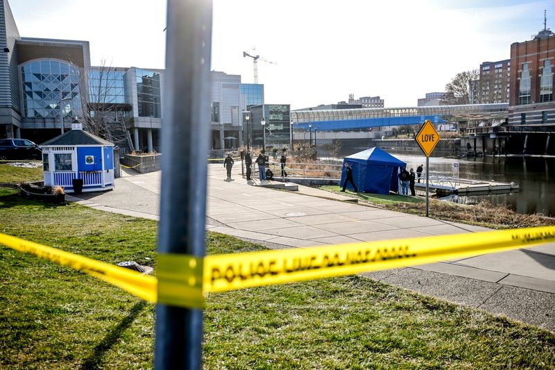 Police investigate the scene where a body was recovered from the Grand River on Tuesday, Dec. 23, 2025, at Rotary Park in downtown Lansing.