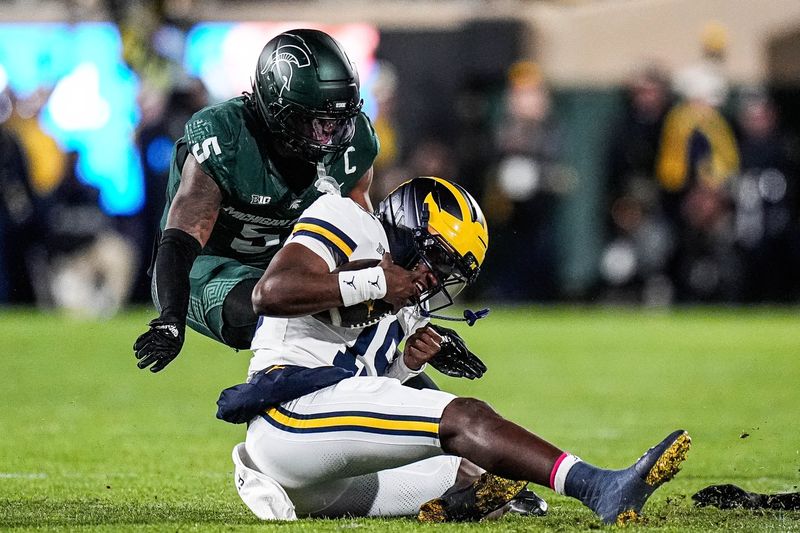 Michigan quarterback Bryce Underwood (19) runs against Michigan State linebacker Jordan Hall (5) during the first half at Spartan Stadium in East Lansing on Saturday, October 25, 2025.