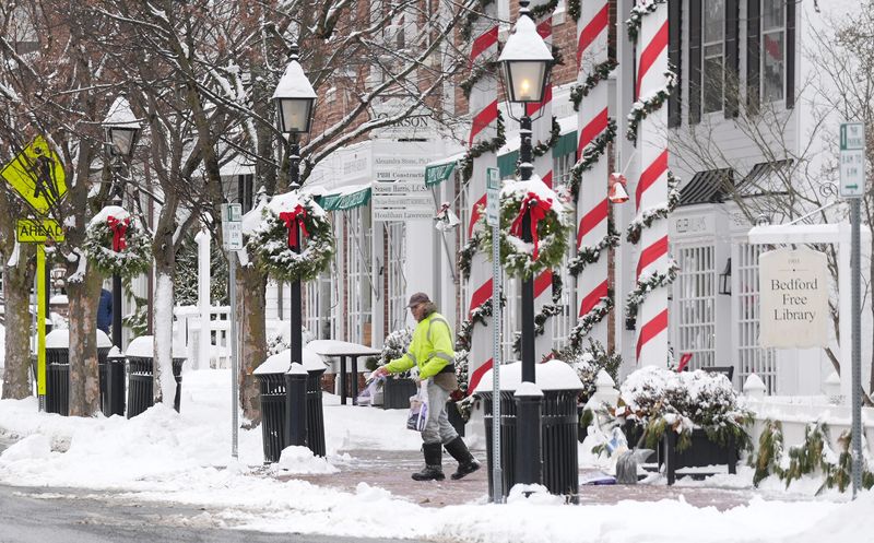 A workers throws rock salt along the sidewalk outside the Bedford Free Library in Bedford Village Dec. 27, 2025.